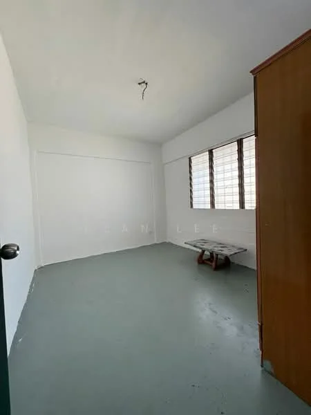 Room features: white painted walls, grey concrete flooring, three vertical sliding windows, single light fixture on ceiling, wooden wardrobe, wooden bench.