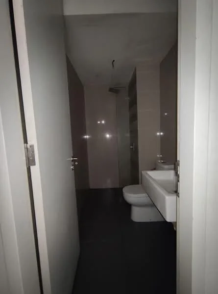 Bathroom features: white wall tiles, grey floor tiles, one-piece toilet, wall-mounted sink, shower area with glass partition, ceiling light fixture, mirror above sink; style: modern.
