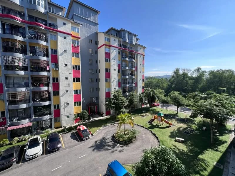 Exterior type: mid-rise condominium; features: colorful facade with red and yellow accents, balconies on each floor, landscaped garden area, children's playground, manicured lawn, parking lot with visible cars, surrounded by greenery, multiple storeys, clear blue sky; style: modern.