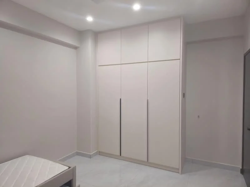 Room features: light grey painted walls, white ceiling, recessed LED downlights, white floor tiles, built-in wardrobe with sliding doors, empty bed frame, single window, neutral decor; style: modern.