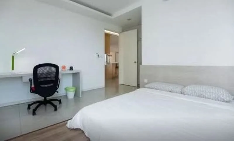 Bedroom features: queen-size bed with white bedding, light grey upholstered headboard, desk with white surface, black office chair, green waste bin, white painted walls, light-colored flooring, recessed ceiling lights; style: modern.
