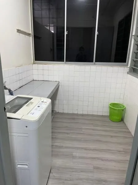 Laundry features: front-load washing machine, grey laminate countertop, white tiled walls, light wood-look vinyl flooring, window with metal grille, green plastic laundry basket, wall-mounted shelf, sink with faucet.