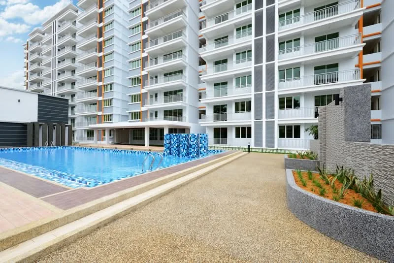 Exterior type: mid-rise condominium; features: swimming pool, pool deck with loungers, landscaped garden area, manicured lawn, modern facade with glass and concrete, balconies on upper floors, parking area, decorative stone wall, paved walkway; style: modern.
