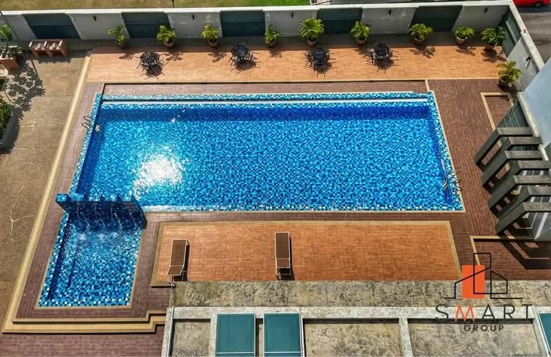 Exterior type: swimming pool deck; features: infinity pool, pool deck with loungers, mosaic tile pool finish, surrounding landscaped area, sun loungers, potted plants, wooden decking, water feature, seating area; style: modern.