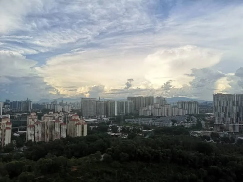 Exterior type: high-rise condominium; features: city skyline, surrounded by greenery, multiple high-rise buildings, urban landscape, cloudy sky, distant mountains, varied building heights, residential blocks, commercial buildings, open view; style: modern.