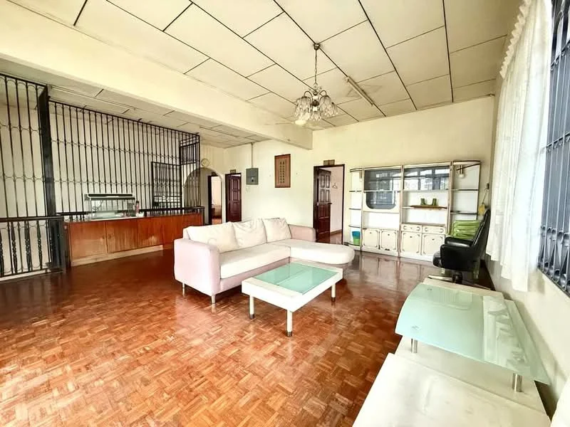 Living features: parquet wood flooring, white painted walls, exposed ceiling with grid panels, 3-seater fabric sofa in light pink, glass coffee table, decorative chandelier, built-in shelving unit, large windows with metal grills, wooden partition with iron bars, wooden cabinetry, green leather armchair; style: traditional.