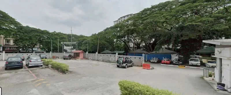 Exterior type: parking deck; features: open-air parking lot, manicured greenery, surrounded by mature trees, multiple parked cars, security barriers, fenced perimeter; style: modern.