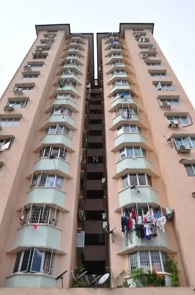 Exterior type: mid-rise condominium; features: peach painted facade, balconies with glass railings, multiple air conditioning units visible, laundry hanging on balconies, satellite dish on balcony, approximately 10-storey high-rise, recessed balconies, windows with security grills; style: modern.
