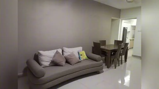 Living features: grey fabric sofa with cushions, 4-seater dining table, white tiled flooring, light grey painted walls, recessed ceiling lights, open layout to kitchen, decorative throw pillow, wall-mounted light fixture; style: modern. Kitchen features: stainless-steel fridge, white cabinetry, countertop, open layout to living area; style: modern.
