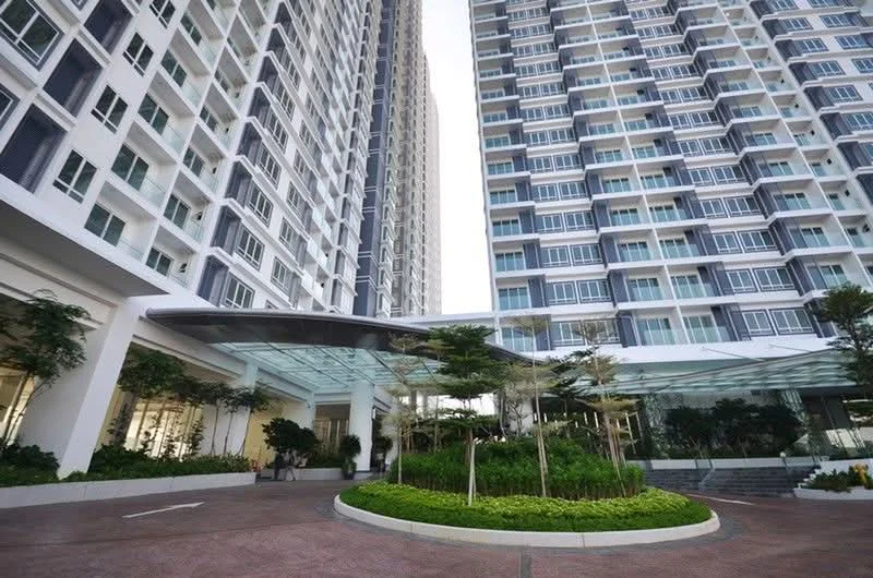 Exterior type: high-rise condominium; features: glass curtain wall, white painted facade, manicured landscaping, entrance with glass canopy, paved walkway, surrounded by greenery, multiple storeys, balconies on upper floors; style: modern.
