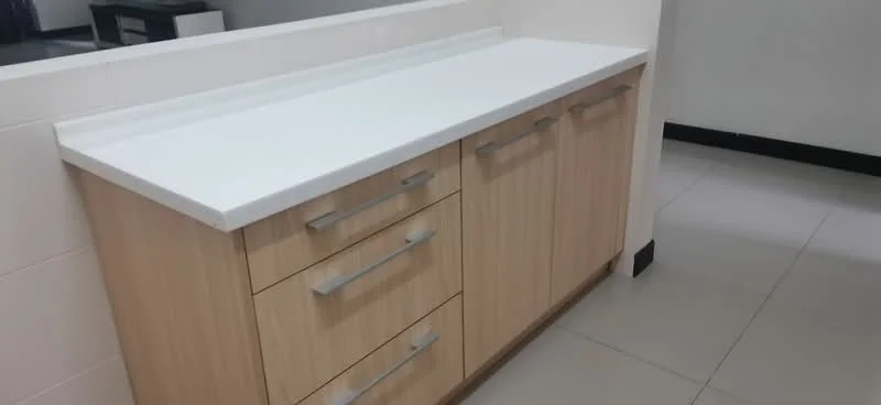 Room features: white countertop, light wood cabinetry, three drawers, two cabinet doors, metal handles, smooth surface, tile flooring, neutral wall color; style: modern.