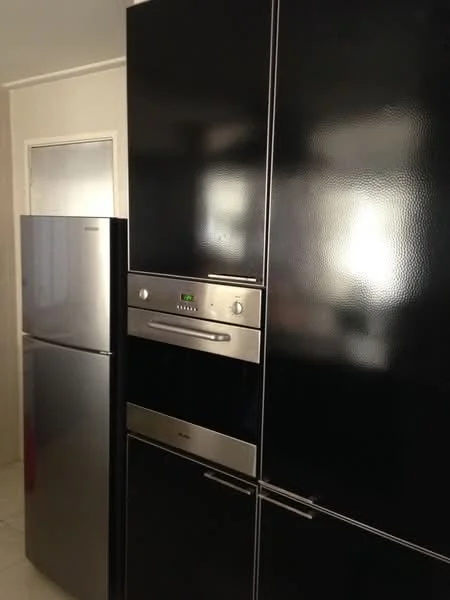 Kitchen features: black refrigerator, stainless-steel built-in oven, black cabinetry, white tiled flooring, wall-mounted oven, silver handles, integrated design, modern appliances; style: modern.