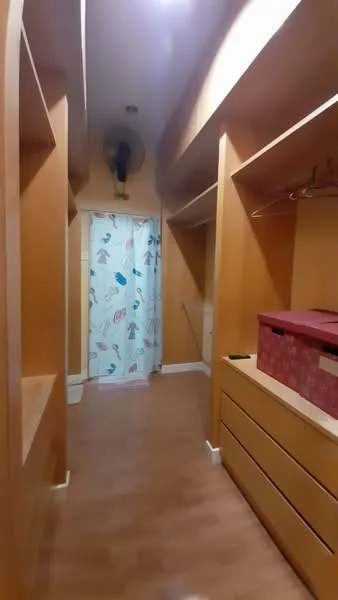 Room features: wooden flooring, orange painted walls, built-in shelving units, hanging rods for clothing, drawers for storage, curtain for privacy, ceiling fan; style: modern.