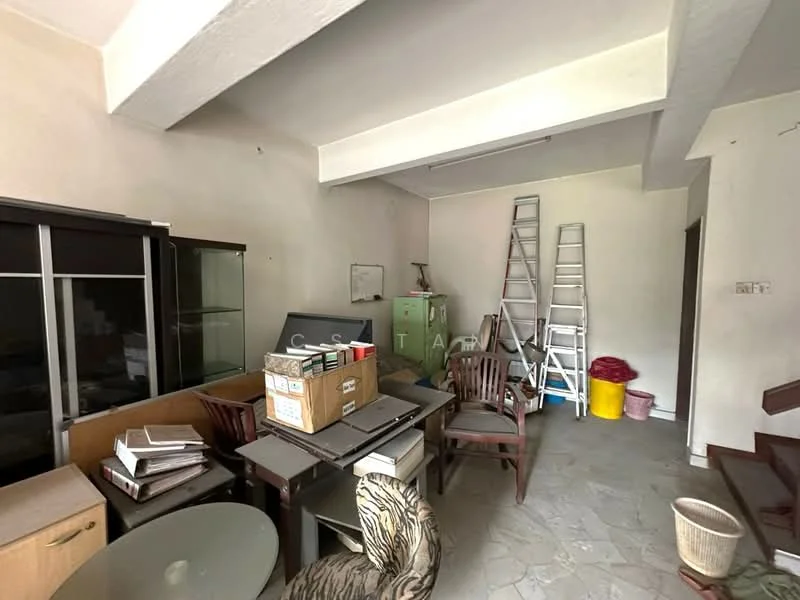 Room features: white painted walls, exposed ceiling beams, grey stone flooring, wooden dining table, wooden chairs, glass display cabinet, stack of boxes, ladders, plastic storage bins, waste basket.