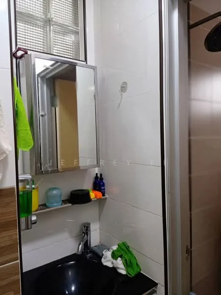 Bathroom features: black countertop, single-bowl sink, chrome faucet, framed mirror, shower enclosure, tile cladding on walls, green towel, various toiletries on shelf.