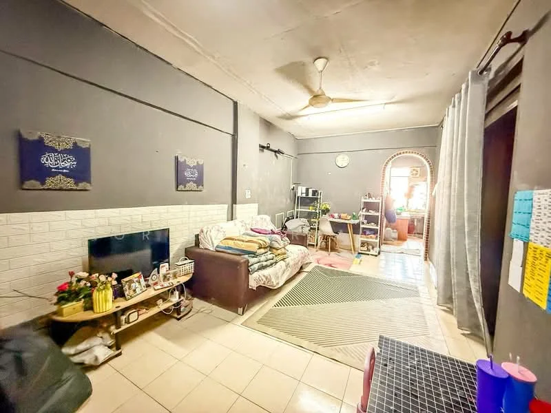 Living features: grey painted walls, white tiled flooring, ceiling fan, sofa with floral pattern, wooden coffee table, wall-mounted TV, decorative wall art, curtains, area rug, clock on wall, open doorway, potted plants.