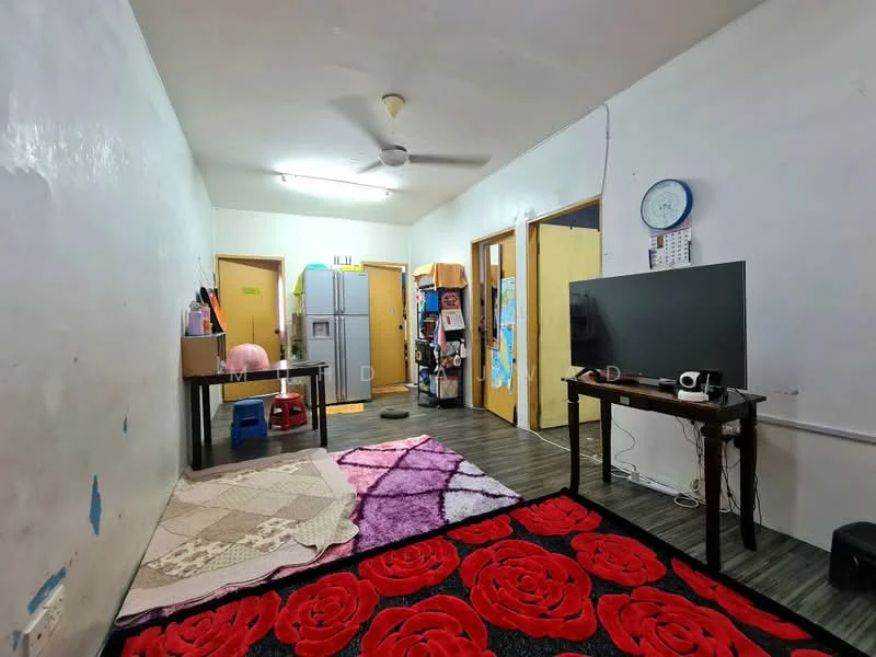 Living features: white painted walls, vinyl plank flooring, 5-blade ceiling fan, wall-mounted TV, wooden coffee table, black TV console, large area rug with floral pattern, refrigerator, two wooden doors leading to other rooms, decorative wall clock.