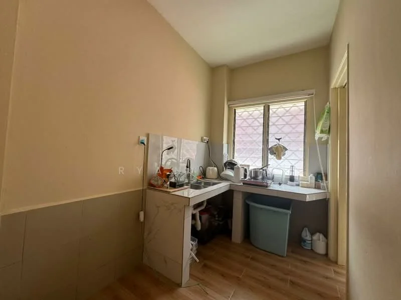 Kitchen features: white painted walls, light brown tiled flooring, L-shaped countertop, stainless-steel sink, chrome pull-down faucet, window with grid pattern, kitchen appliances including kettle and toaster, plastic trash bin, storage cabinet under the sink.