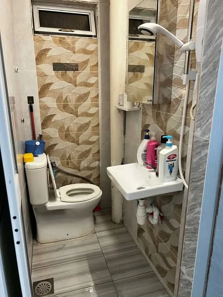 Bathroom features: one-piece toilet, wall-mounted sink, chrome wall-mounted faucet, shower with handheld shower head, mirror above sink, tile cladding with floral pattern, grey ceramic tile flooring, white wall, shower curtain rod, cleaning supplies on shelf; style: modern.
