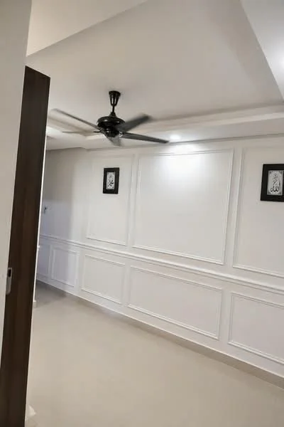 Room features: white painted walls with wainscoting, polished ceramic tile flooring, tray ceiling, 5-blade ceiling fan, framed artwork on walls, recessed downlights; style: modern.