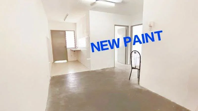 Room features: white painted walls, concrete flooring, fluorescent ceiling lights, window with natural light, open layout, chair, kitchen area visible, doorway leading to another room; style: minimalist.
