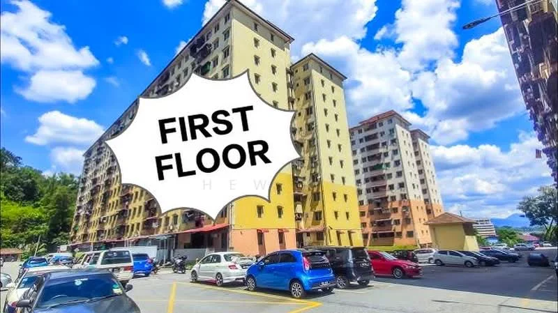 Exterior type: low-rise apartment block; features: multiple-storey building, parking lot with visible cars, surrounded by greenery, balconies on upper floors, cream painted facade, windows with metal grilles, first floor signage, cloudy sky, urban setting; style: modern.