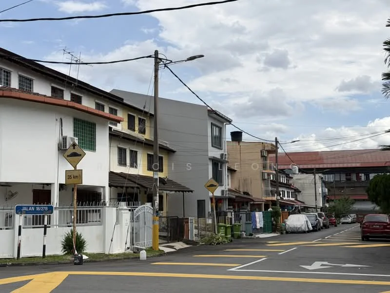 Exterior type: linked terrace house; features: two-storey linked terrace houses, white painted facade, grey painted facade, balconies on upper floors, visible air conditioning units, street signage, paved road, yellow road markings, manicured greenery, utility poles, cloudy sky; style: modern.