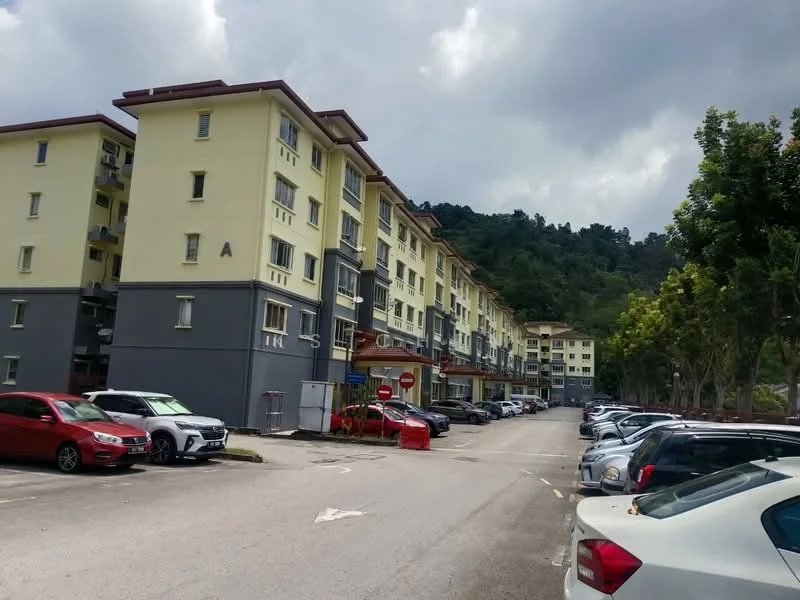 Exterior type: low-rise apartment block; features: yellow painted facade, red tiled roof, multiple storeys, parking lot with marked spaces, landscaped area with trees, surrounded by greenery, road access, entrance with stop sign; style: modern.