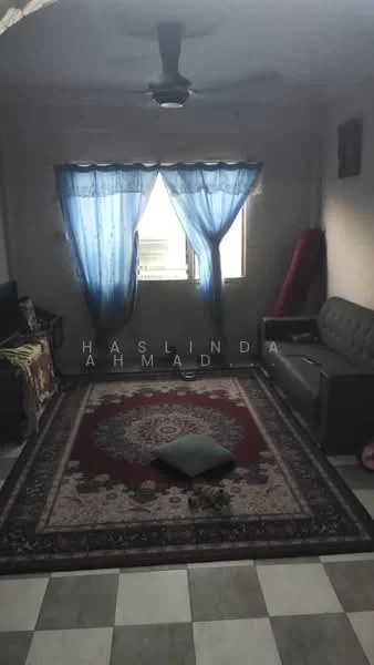 Living features: 3-seater fabric sofa in grey, area rug with intricate pattern, ceiling fan, floor-to-ceiling window with blue sheer curtains, wall-mounted TV, decorative wall art, tiled flooring in a checkerboard pattern, cushion on the floor.