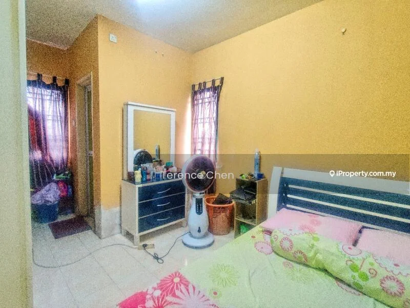 Bedroom features: yellow painted walls, tiled flooring, queen-size bed with floral bedding, wall-mounted mirror, dressing table, 2 windows with sheer curtains, ceiling fan, plastic laundry basket, decorative items on dresser, floor fan.