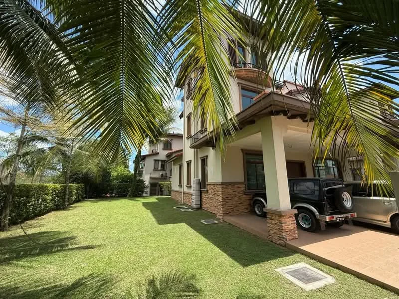 Exterior type: detached bungalow; features: two-storey building, cream painted facade, stone cladding at base, pitched tile roof, manicured lawn, surrounded by palm trees, driveway with interlocking pavers, outdoor space with grass, balcony on upper floor, windows with decorative grills; style: tropical-modern.