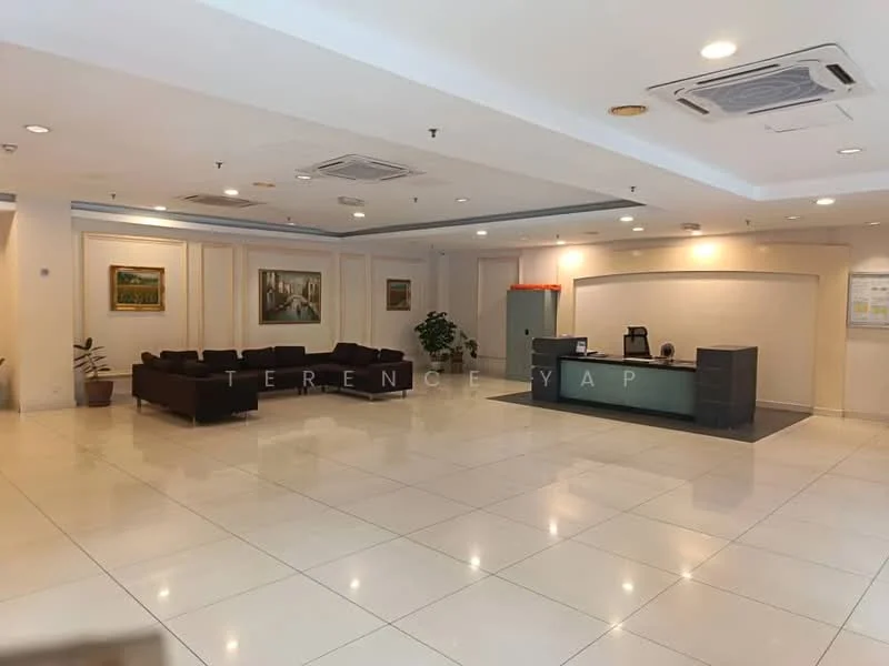 Lobby features: white tiled flooring, recessed ceiling lights, cream painted walls, two framed paintings on walls, dark brown fabric sofa set, reception desk with grey surface, green potted plant, air conditioning vents on ceiling; style: modern.