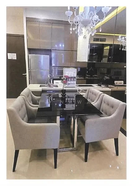 Dining features: black glass dining table, 4 upholstered dining chairs in light grey, chandelier with multiple bulbs, kitchen cabinetry in dark wood finish, stainless-steel fridge, built-in oven, black countertop, recessed lighting, cream tiled flooring, decorative vase on table; style: modern.