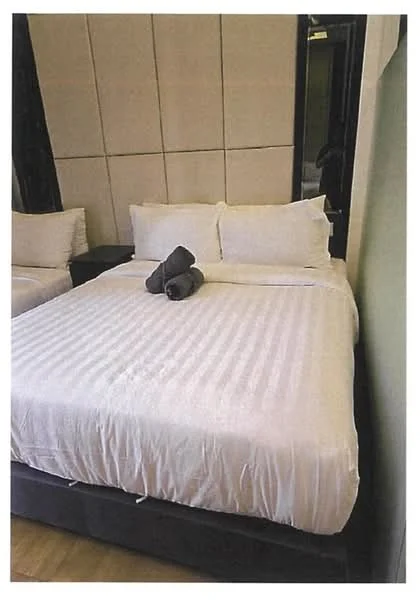 Bedroom features: king-size bed, white bedding, two white pillows, grey towels, wooden flooring, decorative throw pillows, wall-mounted mirror, panelled wall, black accent wall; style: modern.