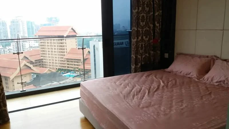 Bedroom features: king-size bed with pink bedding, floor-to-ceiling windows, balcony access, curtains with floral pattern, wooden flooring, decorative wall paneling, city view, nightstand with lamp; style: modern; view: city.