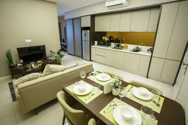 Dining features: 6-seater dining table, upholstered dining chairs, table setting with plates and cutlery, decorative centerpiece, greenery in ceramic pot; style: modern. Kitchen features: L-shaped kitchen layout, white cabinetry, black countertop, built-in oven, stainless-steel fridge, kitchen appliances visible, gold backsplash, recessed downlights; style: modern. Living features: 3-seater fabric sofa, coffee table, TV console, wall-mounted TV, decorative plants; style: modern.