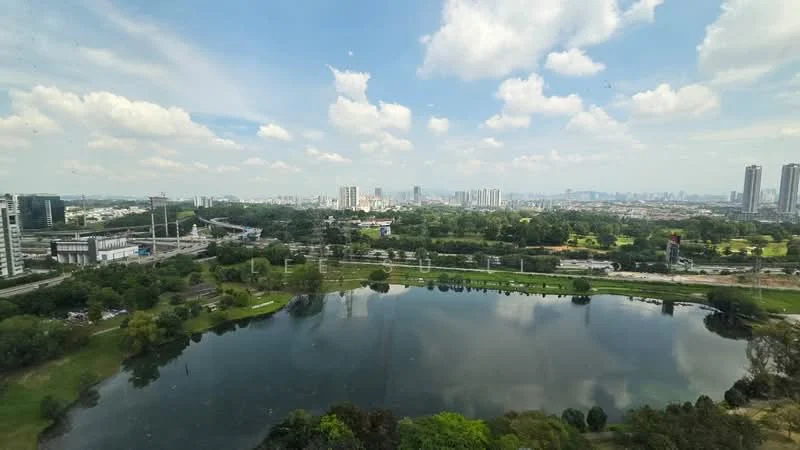 Exterior features: city skyline in background, large body of water, green parkland, urban landscape, cloudy blue sky, high-rise buildings in distance, roadway visible, lush greenery; style: modern.