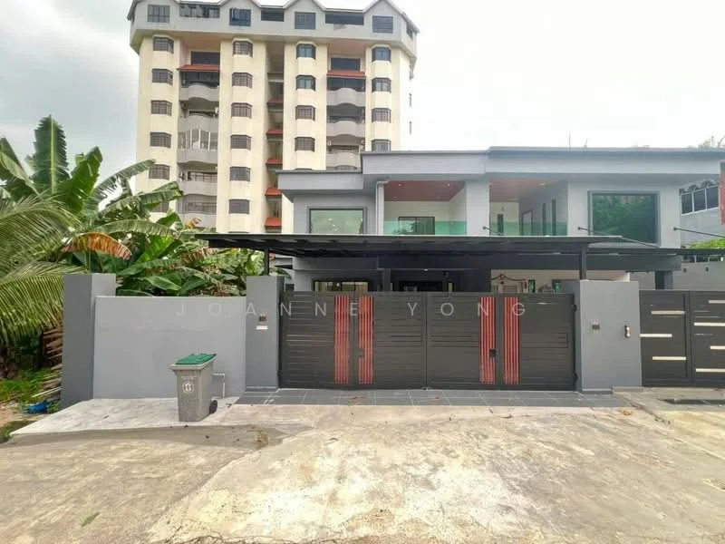 Exterior type: detached bungalow; features: grey painted facade, red accent features on gate, flat roof, manicured lawn, paved driveway, surrounded by tropical landscaping, multiple-storey building in background, gated entry with sliding gate; style: modern.