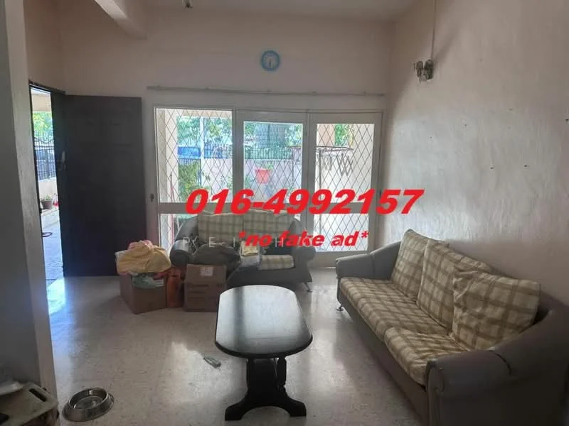 Living features: 2-seater fabric sofa in grey, 3-seater fabric sofa with checkered pattern, wooden coffee table, large windows with security grille, light-colored walls, tile flooring, decorative wall light, boxes and items in the corner.