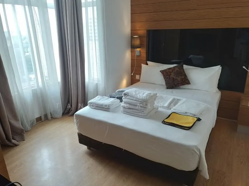 Bedroom features: queen-size bed, upholstered headboard, white bedding, decorative pillow, wooden accent wall, floor-to-ceiling windows, sheer curtains, grey curtains, laminate flooring, nightstand with lamp, stacked towels, yellow towel; style: modern; view: city.