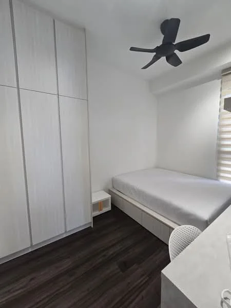 Bedroom features: queen-size bed, light grey bedding, white walls, built-in wardrobe with light wood finish, white bedside table, black ceiling fan with 3 blades, window with horizontal blinds, dark wood laminate flooring, study desk with white chair; style: modern.