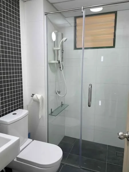 Bathroom features: glass shower enclosure, rain shower head, handheld shower, white ceramic toilet, single-sink vanity with white cabinet, chrome basin mixer, wall-mounted mirror, black tiled accent wall, grey ceramic tile flooring, window with horizontal slats, glass shelf in shower area, toilet paper holder; style: modern.