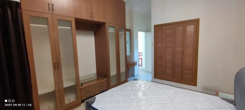 Bedroom features: wooden wardrobe with glass doors, built-in desk, wooden paneling on wardrobe, queen-size bed, white mattress, light-colored walls, curtains, laminate flooring; style: modern.
