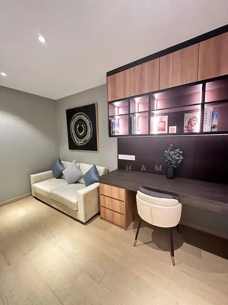 Study features: light wood flooring, grey painted walls, built-in wooden desk, white upholstered chair, cream fabric sofa, decorative wall art, shelves with books and decor items, recessed ceiling lights; style: modern.