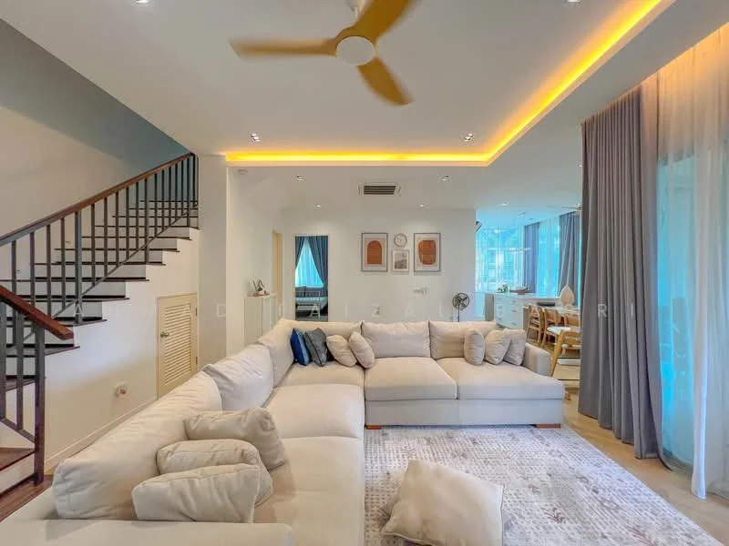 Living features: L-shape sectional sofa in cream fabric, decorative cushions, area rug with geometric pattern, ceiling fan with light, recessed downlights, wall-mounted artwork, large windows with sheer curtains, wooden staircase, open-plan layout leading to dining area, light wood flooring, wall-mounted air conditioning unit, crown moulding, LED strip lighting along ceiling; style: modern.