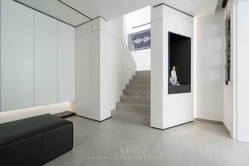 Room features: white painted walls, grey tile flooring, staircase with white risers, built-in cabinetry, black leather bench, recessed lighting, niche with decorative item, minimalist design; style: modern.