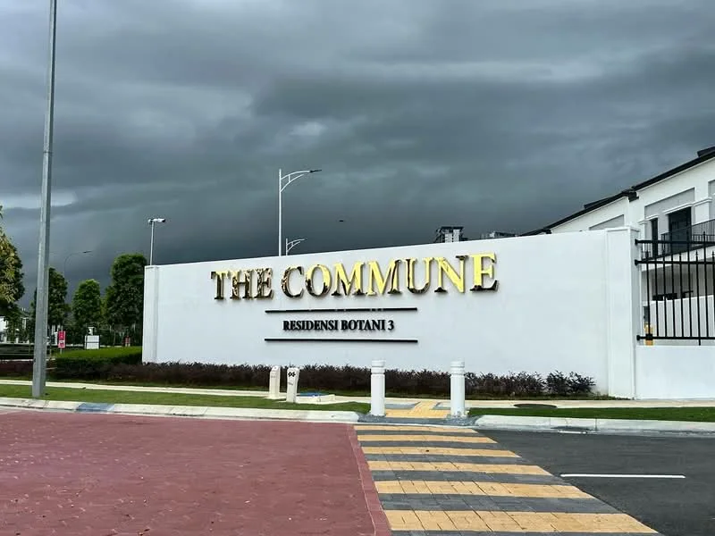 Exterior features: white painted facade, illuminated signage, landscaped garden, paved driveway, street lighting, stormy sky, greenery in background; style: modern.