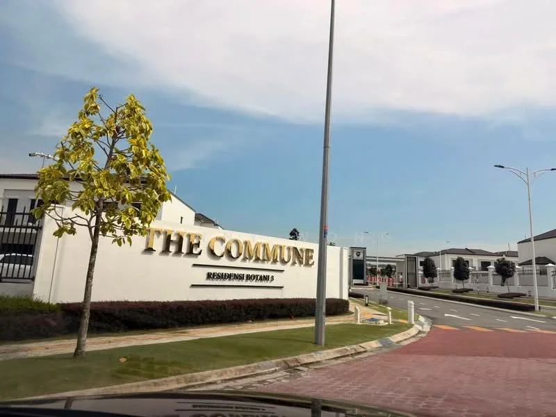 Exterior type: residential development; features: signage with 'THE COMMUNE', landscaped entrance with trees, paved driveway, street lighting, surrounding greenery, modern architectural design, gated entry, visible residential units in background; style: modern.
