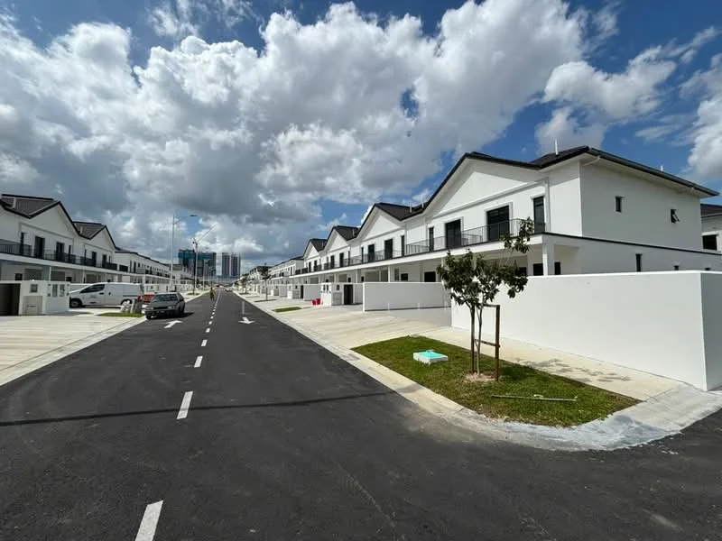 Exterior type: linked terrace house; features: white painted facade, two-storey buildings, flat roof, manicured lawn, paved walkway, driveway with interlocking pavers, surrounded by greenery, clear blue sky, cloudy weather, street view, parking spaces visible; style: modern.