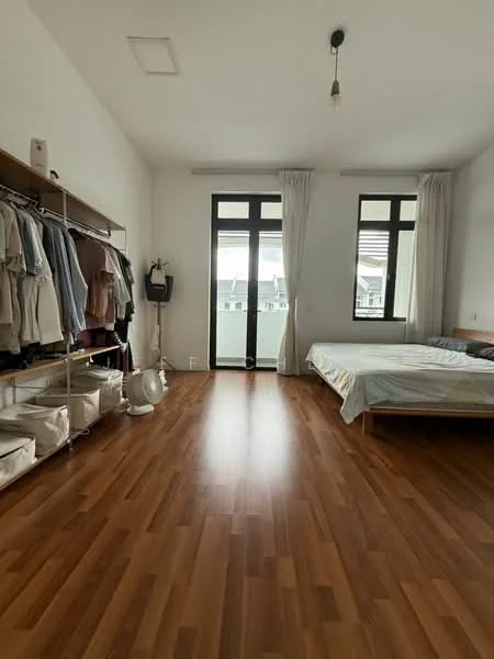 Bedroom features: wooden flooring, white painted walls, two windows with black frames, double bed with light bedding, open wardrobe with hanging clothes, storage boxes on the floor, ceiling light fixture, wall-mounted fan, curtains, balcony door; style: minimalist.
